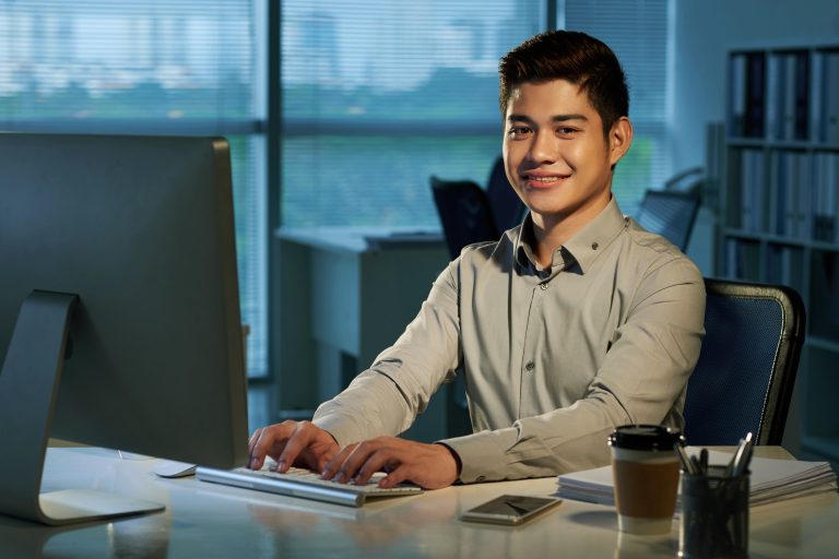 smiling filipino sitting infront of desk
