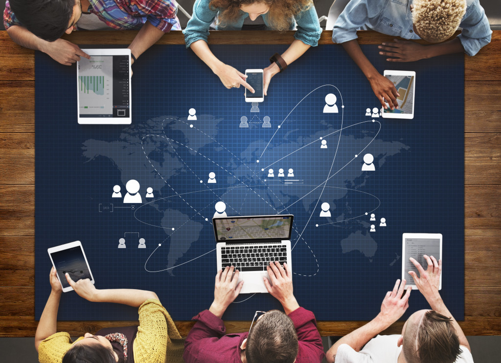 People using various devices on a table with a map