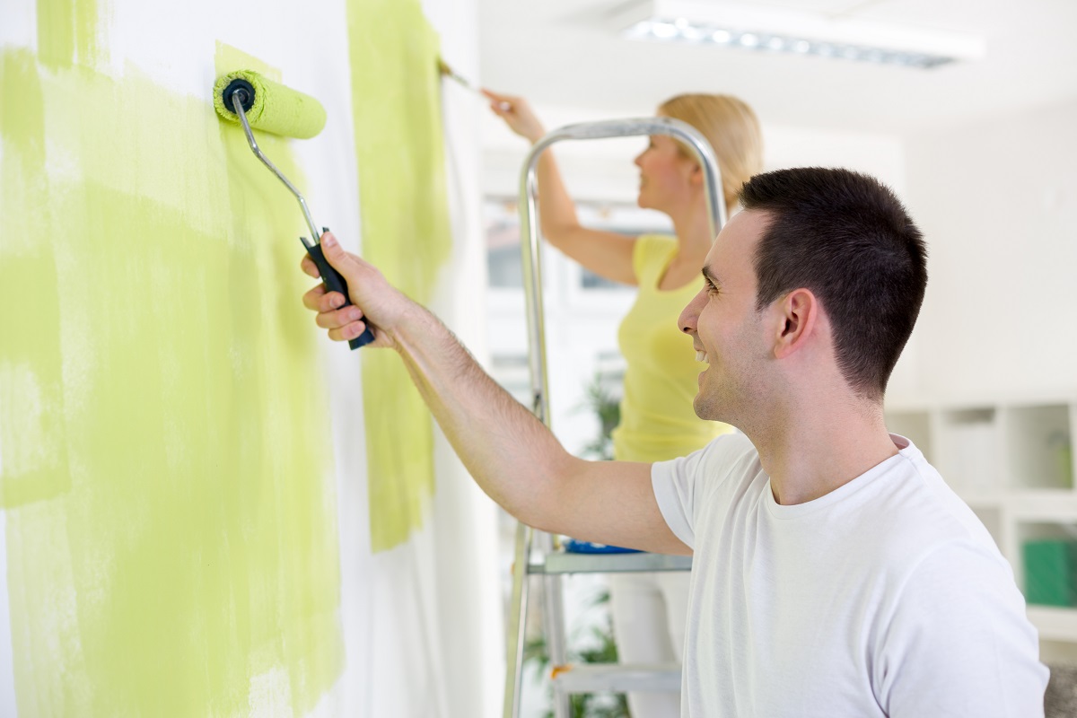 Young couple painting the walls of their home.